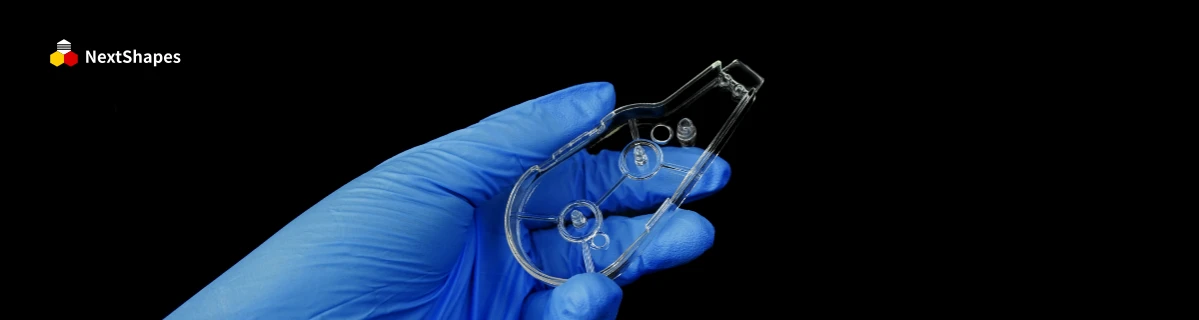 Side-angle view of a 3D printed transparent component held in a blue nitrile glove, made with NextShapes 8001 resin, demonstrating high light transmittance and smooth, precise surface details