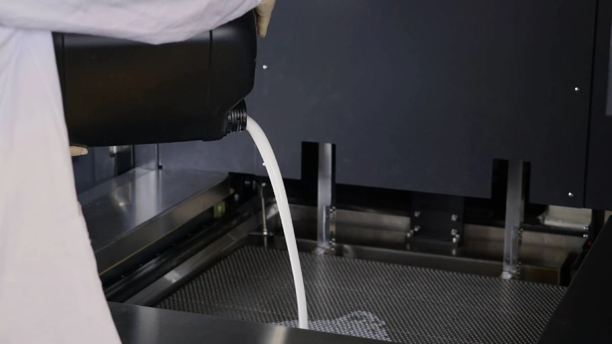 Operation view of pouring NextShapes Precision Clear resin into SLA 3D printer, demonstrating scalable industrial production workflow