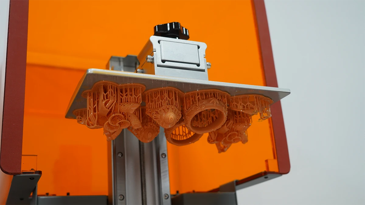 Array of 3D printed jewelry models on print bed made with NextShapes High Resolution 8K Pro Red Wax Resin, demonstrating high print success rate and scalable production