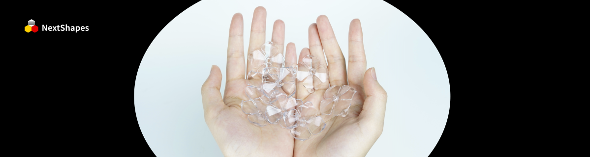 Hands holding multiple crystal-clear petal-shaped 3D printed samples made with NextShapes 8001 transparent resin, showcasing zero bubbles and high light transmittance.