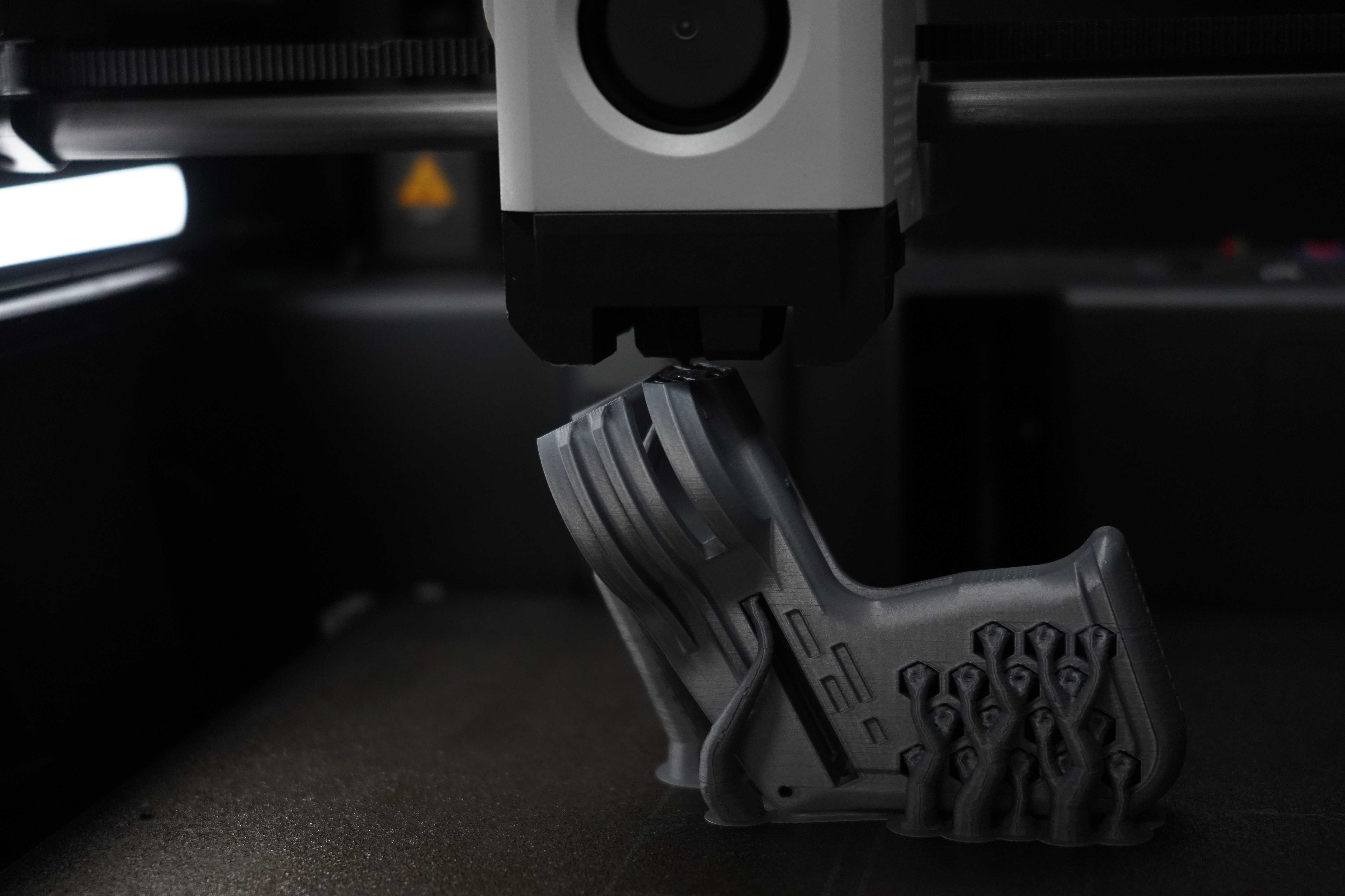 FDM 3D printer extruding a black prototype part made with NextShapes Standard PLA filament, showing high-precision layer adhesion