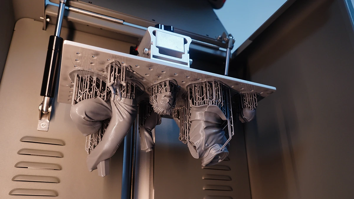 Display of 3D printed figurine models with support structures during printing made with NextShapes Standard Pro Resin, showcasing high print success rate and support stability