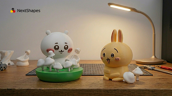 Two cute Chiikawa-style anime collectible figures 3D printed with NextShapes Standard PLA filament on wooden desk, highlighting ultra-smooth surface finish and low shrinkage precision for IP character production