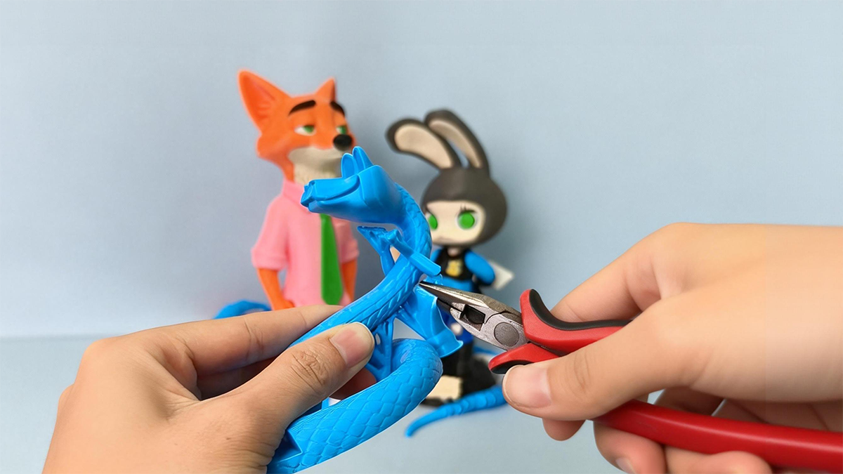 Hands trimming support structures from a 3D printed snake model made with PETG HF filament